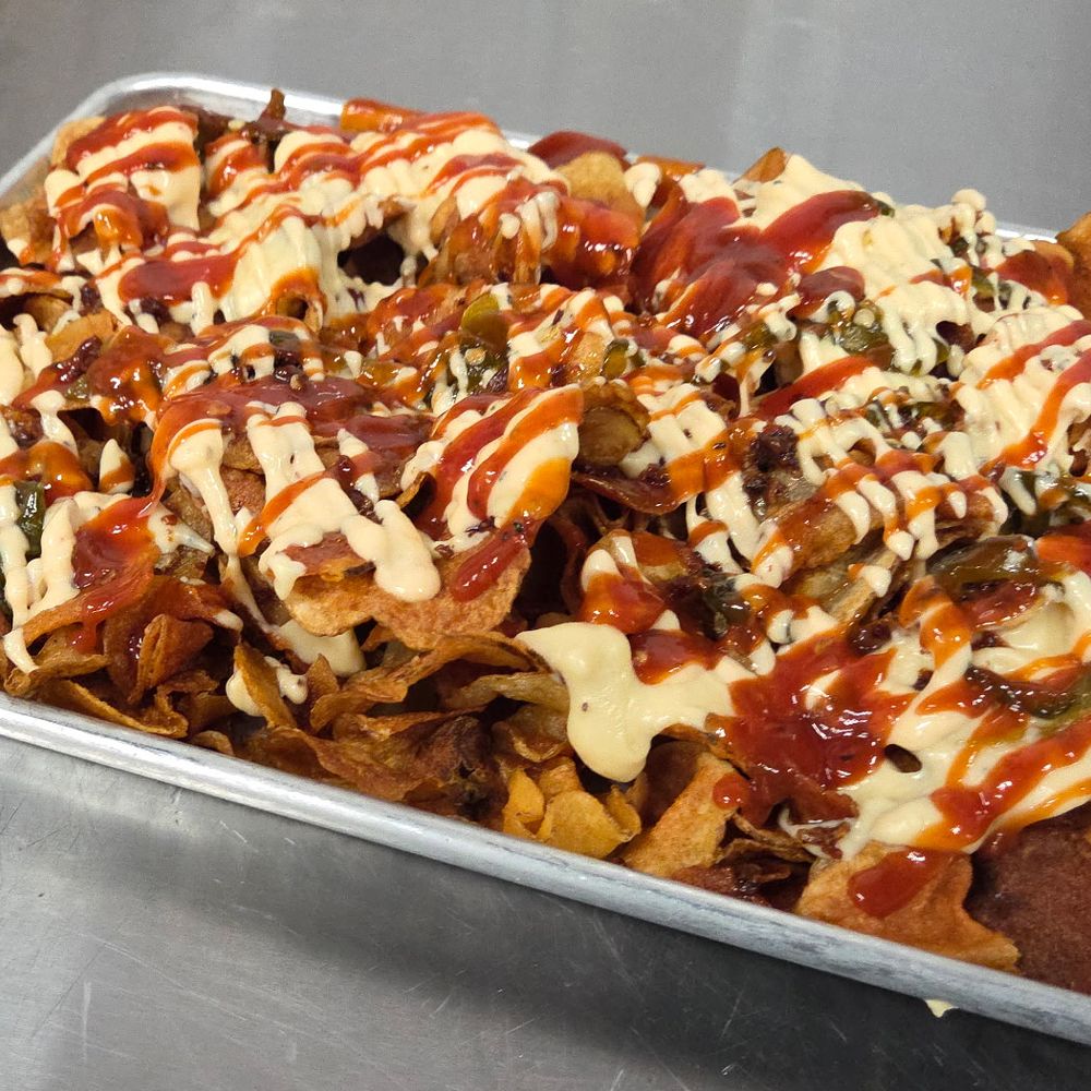 The Good Stuff &mdash; house-made Tallow Chips loaded with jalape&ntilde;o queso, candied jalape&ntilde;os, bacon, and drizzles of house BBQ and Flip Sauce on a metal tray