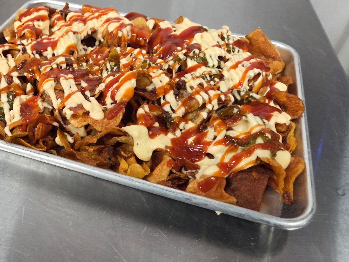 The Good Stuff &mdash; a sheet tray of house-made Tallow Chips loaded with jalape&ntilde;o queso, candied jalape&ntilde;os, bacon, and dual drizzles of house BBQ and Flip Sauce