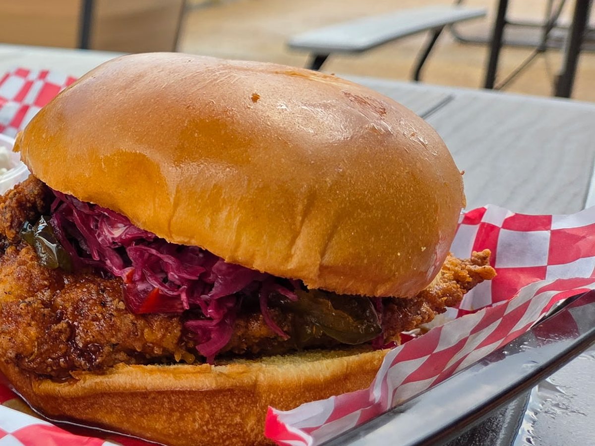 The Hot Honey Chicken Sandwich &mdash; house-battered fried chicken on a brioche bun with pickled slaw and candied jalape&ntilde;o, served in a checkered basket